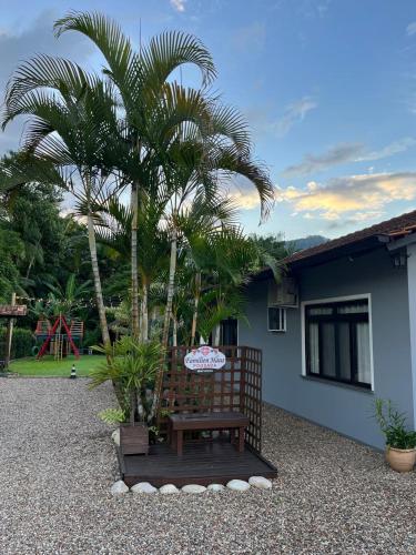 a bench in front of a house with a palm tree at Familien Haus Pousada in Pomerode