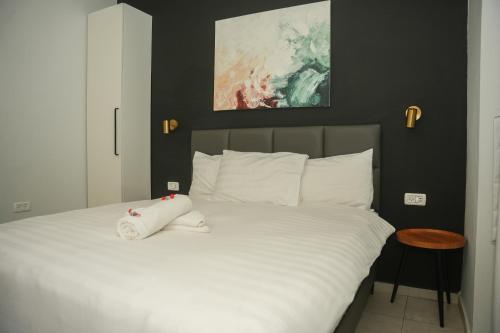 a bedroom with a bed with white sheets and a painting at White Moon Inn in Jerusalem