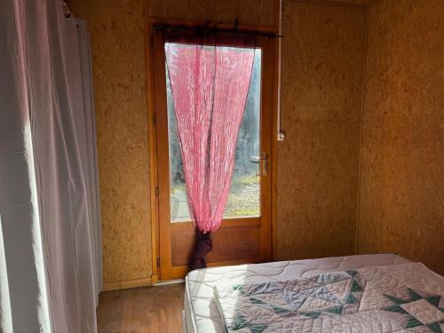 a bedroom with a window with a pink curtain at Chalet dans la nature in Palisse