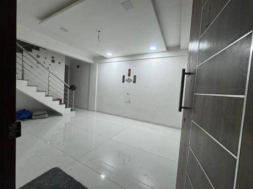 a white room with a staircase and a door at Harmony Palace Guest House in Nashik