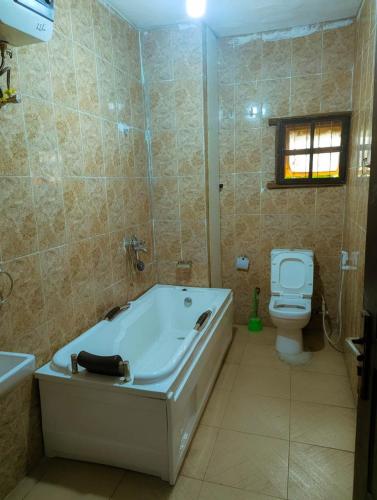 a bathroom with a bath tub and a toilet at Frenezia Hotel and Apartment Ikeja GRA in Ikeja