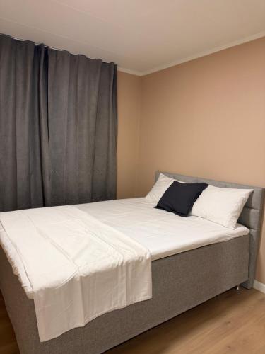 a bed with white sheets and a black pillow on it at Gardermoen Airport, 5Min in Sand