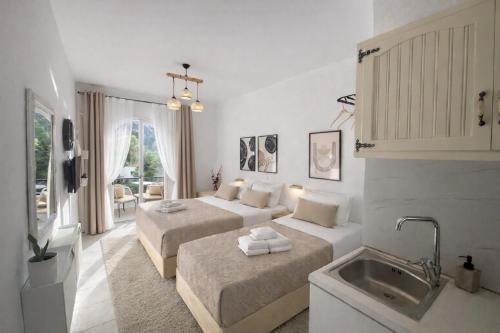 a white room with two beds and a sink at Ameli Studio ,Balcony with Mountain View, Kitchenette, 1km to Beach by likeyourhome in Corfu
