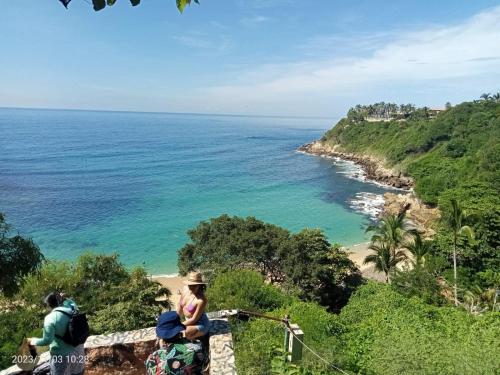 a group of people sitting on a wall looking at the ocean at Casa de ámbar cuatunalco in Cuatunalco