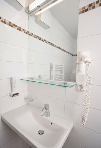 a white bathroom with a sink and a mirror at Lemon Living Self-Check-in in Ottensheim