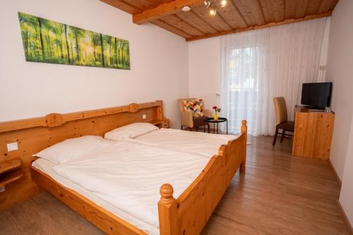 a bedroom with a wooden bed and a television at Lemon Living Self-Check-in in Ottensheim