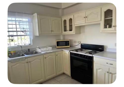 une cuisine avec des armoires blanches et une plaque de cuisson noire dans l'établissement Sunset Bliss, à Castries