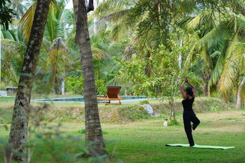a woman doing yoga in a park with palm trees at Welpalla Signature in Welpalla