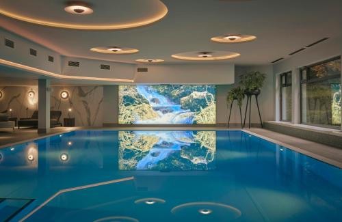 a swimming pool in a hotel room with a painting on the wall at Leonardo Royal Hotel Baden- Baden in Baden-Baden