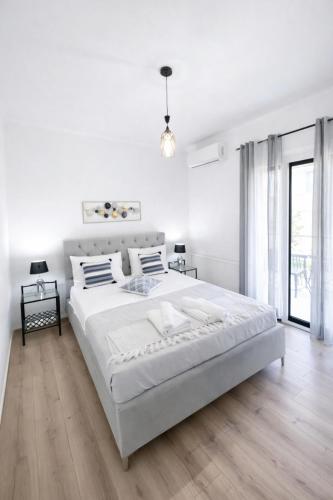 a white bedroom with a large bed and a large window at Liovore Apartments in Lygia