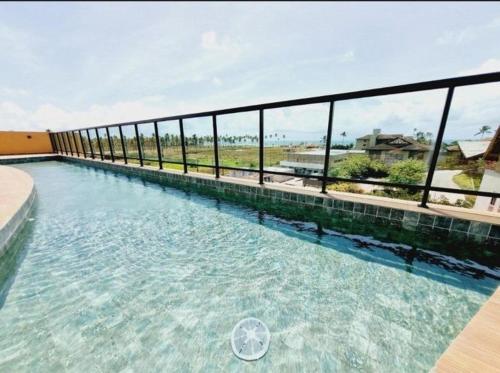 a swimming pool with a fence and some water at Flat Completo Porto de galinhas in Porto De Galinhas