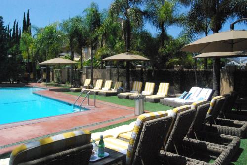 a pool with chairs and umbrellas in front at Hollywood Hotel in Los Angeles