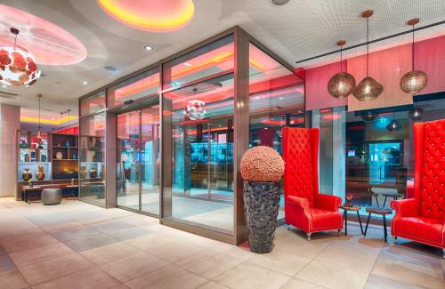 a store lobby with red chairs and a table at Leonardo Hotel Munich City South in Munich