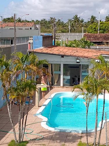 a woman standing next to a swimming pool next to a building at Bio natura in Marechal Deodoro