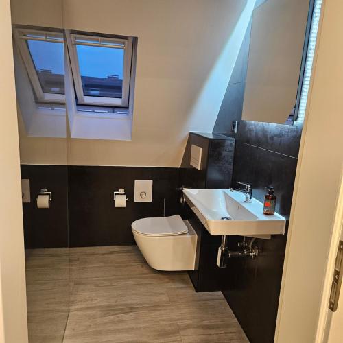 a bathroom with a sink and a toilet and two windows at casa stadio2 in Leverkusen