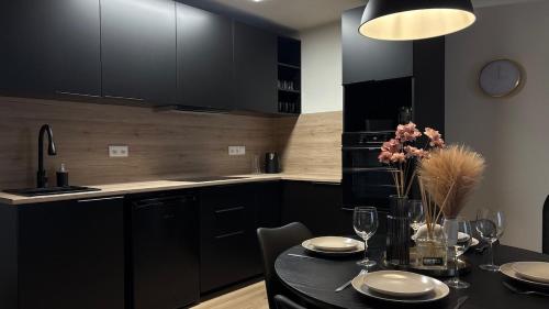 a kitchen with black cabinets and a black table with flowers at Apartmán Jungmannka in Bruntál