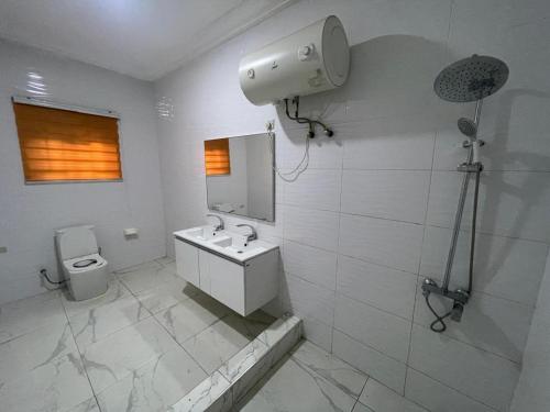 une salle de bains blanche avec un lavabo et des toilettes dans l'établissement Ernest's Haven, à Tema