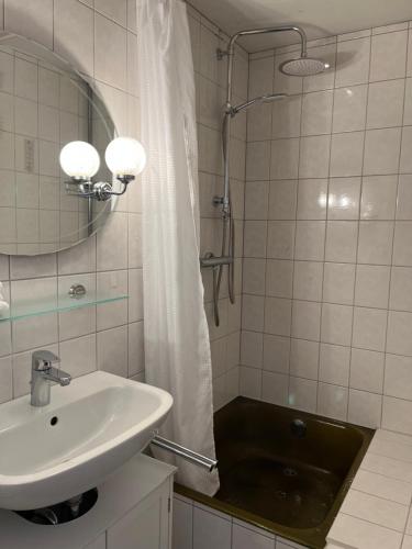 a white bathroom with a sink and a shower at PrivArtZimmer 'Ausfahrt freihalten' in Husum