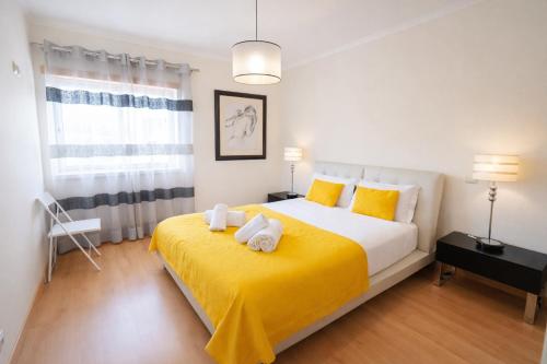 a bedroom with a large bed with yellow sheets and yellow pillows at Dalila's house - Spacious and Comfortable 3-Bedroom Apartment with Garage in Nazaré