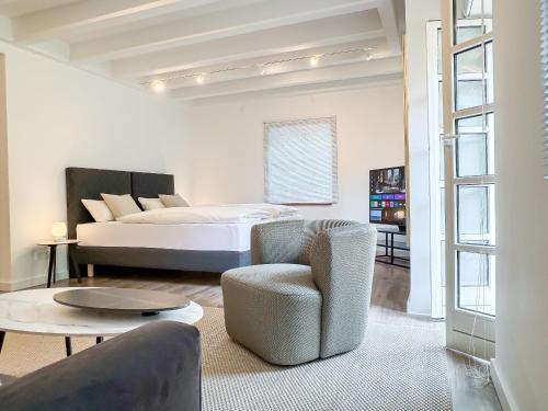 a bedroom with a bed and a chair and a table at Gutshaus am Rhein in Düsseldorf