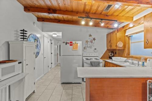 a kitchen with white appliances and a wooden ceiling at Pool, Blocks away from Beach, Dog friendly in Oak Island