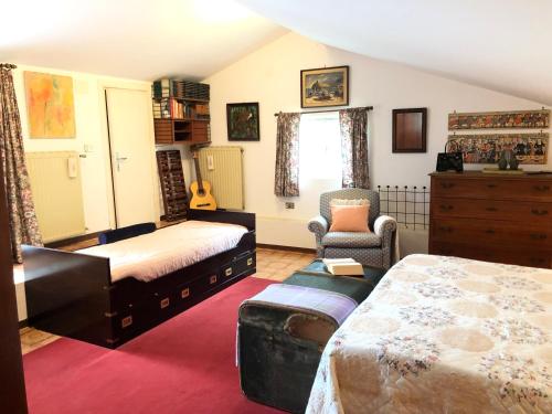 a bedroom with two beds and a chair at Una casa ospitale con giardino in Castel SantʼAngelo