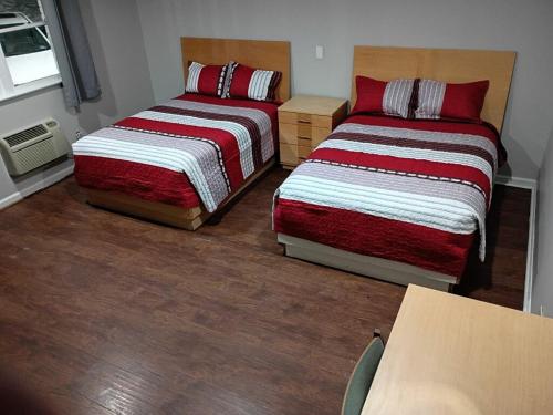 two beds in a small room with wood floors at Bel Air Motor Lodge in Maple Shade
