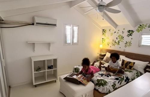 two children sitting on a bed reading books at Habitat Samaná Apartments - Coral Samanà in Los Corozos