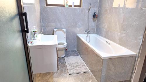 a bathroom with a tub and a toilet and a sink at Witu Apartments in Lusaka