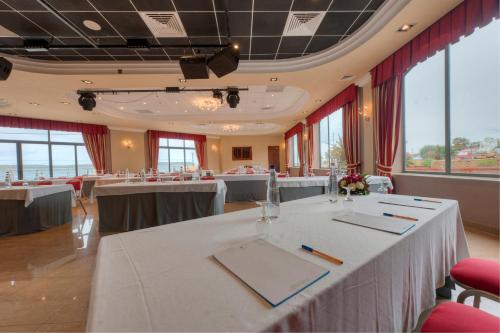 a conference room with tables and chairs and windows at Paradise Bay Resort in Mellieħa