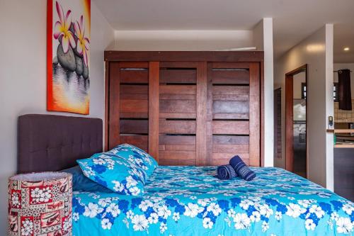 a bedroom with a blue bed with a wooden headboard at Studio Coquet - Mautara Lodge in Bora Bora