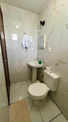 a white bathroom with a toilet and a sink at Suíte Peroba em Maragogi in Maragogi