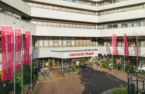 a large building with red flags in front of it at Leonardo Royal Hotel Frankfurt in Frankfurt