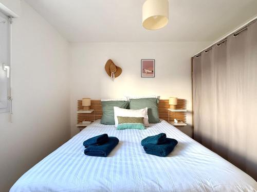 a bedroom with a bed with two blue pillows on it at Le cocon des familles - 2 Chambres in Vannes