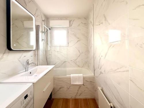 a white bathroom with a sink and a mirror at Le cocon des familles - 2 Chambres in Vannes