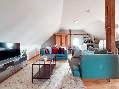 a living room with two blue couches and a tv at Sky Maisonette Pirna Altstadt mit 2 Schlafzimmer und extra großem Wohn-Essbereich in Pirna