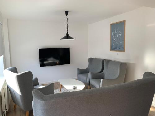 a living room with chairs and a table and a tv at Familiehus in Nakskov