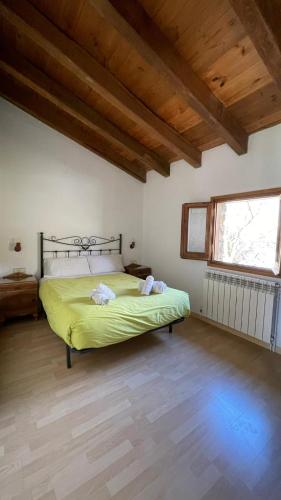 a bedroom with a bed with yellow sheets and a window at Allotjaments rurals Can Punti in Vallfogona de Ripolles