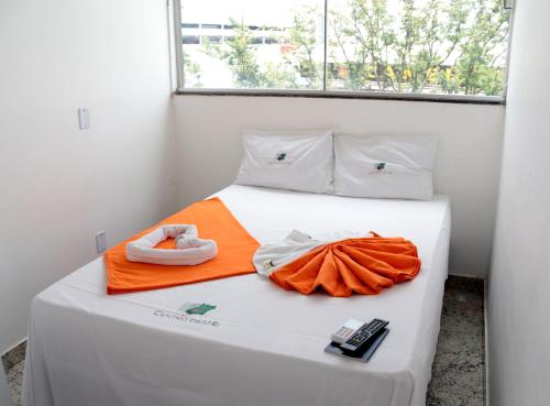 a white bed with an orange towel on it at Hotel Cco Goiânia in Goiânia