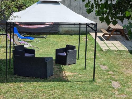 a gazebo with two chairs under it in the grass at Ombre d'été in Ruoms