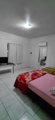 a bedroom with a bed with a red blanket on it at Pousada Familiar 09 in Rio do Sul