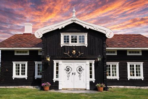a black and white house with a white door at Traditional timber farm with Sauna & Wi-Fi in Baukål