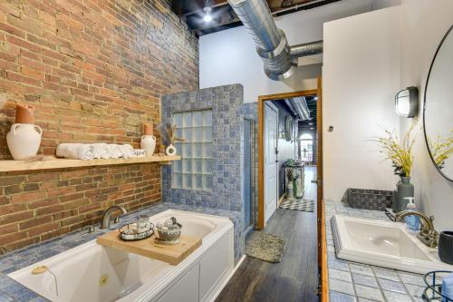 a bathroom with a large tub and a brick wall at Jacuzzi Tub & Full Kitchen: Dowtown Hannibal Loft in Hannibal