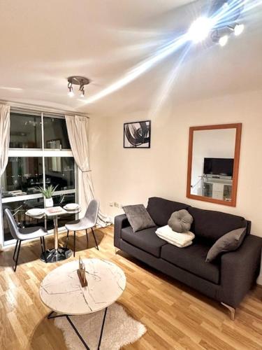 a living room with a black couch and a table at Stylish Luxury 1BR in Chelsea in London