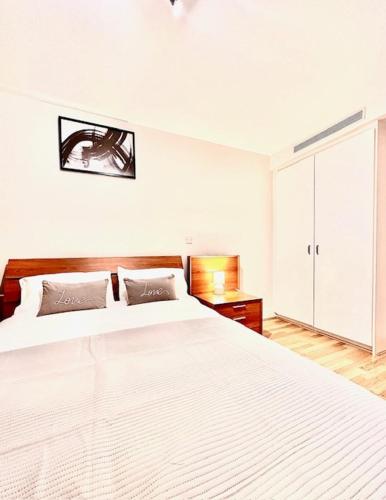 a white bedroom with a large bed and a cabinet at Stylish Luxury 1BR in Chelsea in London