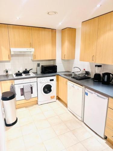 a kitchen with white appliances and wooden cabinets at Stylish Luxury 1BR in Chelsea in London
