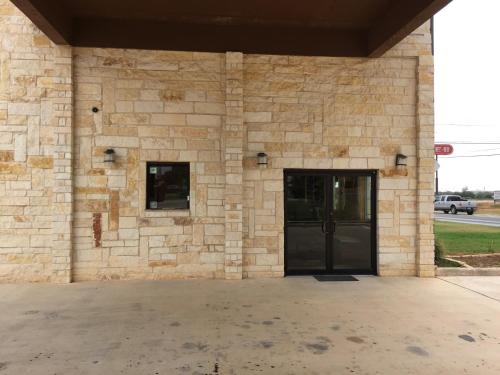 a stone building with a large door and a building at Pearsall Inn and Suites in Pearsall