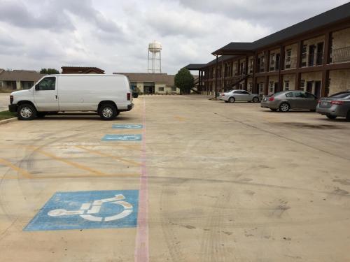a white van parked in a parking lot at Pearsall Inn and Suites in Pearsall