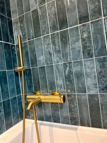 a bath tub with a gold faucet in a bathroom at Blanche maison calme in Neuville-sur-Vanne