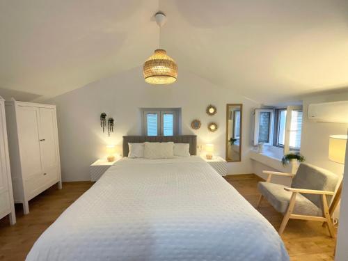a bedroom with a large white bed and a chair at St Peter's Heritage House in Trogir